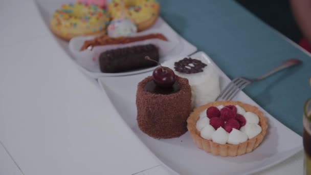 Πλάκα με όμορφα φρέσκα γλυκά σε ένα τραπέζι σε ένα καφέ. — Αρχείο Βίντεο
