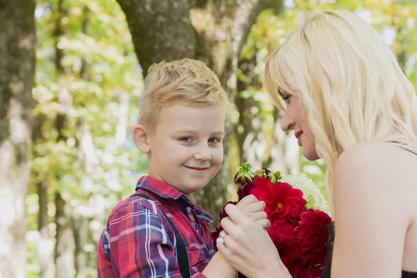 Little beautiful boy gives flowers to mom.