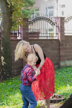 Beautiful happy young family hugs by a tree in the park.