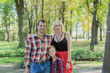 Güzel mutlu genç aile bir şehir parkında yürüyor.