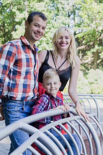 Bela família jovem feliz caminha em um parque da cidade . — Fotografia de Stock