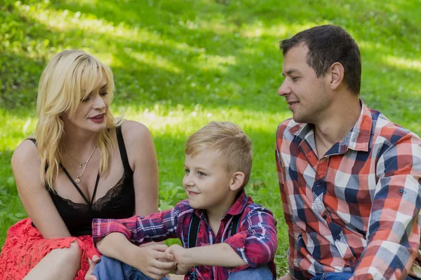 Schöne glückliche Familie ruht sich auf einem Picknick an einem sonnigen Tag aus. — Stockfoto