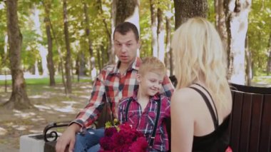 Güzel aile parkta bir bankta oturan ve konuşurken.