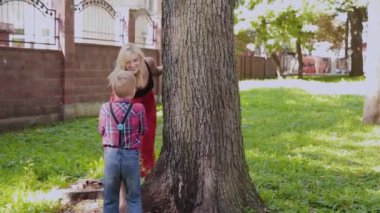 Mutlu neşeli aile sarılma ve parkta ağaç tarafından gülümseyen.