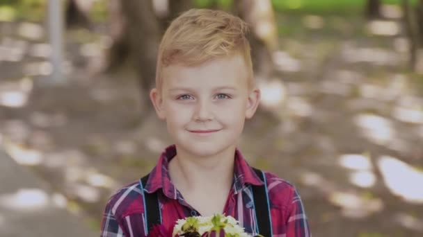 Hermoso niño con un ramo de flores en sus manos . — Vídeo de stock