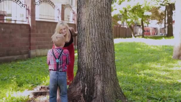 Щаслива весела сім'я обіймає і посміхається на дереві в парку . — стокове відео