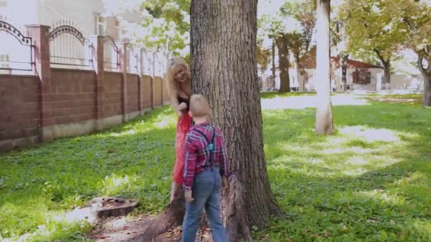 Gelukkig vrolijke familie knuffelen en glimlachend door de boom in het Park. — Stockvideo