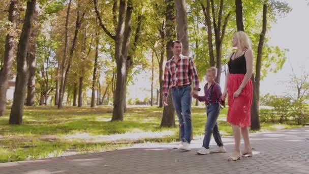 Happy young family walks in the park along the alley. — Stock Video
