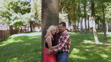 Mutlu neşeli aile sarılma ve parkta ağaç tarafından gülümseyen.