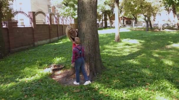 Feliz família alegre abraçando e sorrindo pela árvore no parque . — Vídeo de Stock