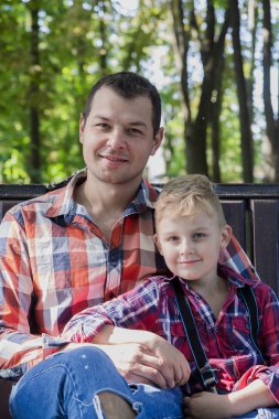 Yakışıklı baba ve oğlu parkta bir bankta oturuyorlar..