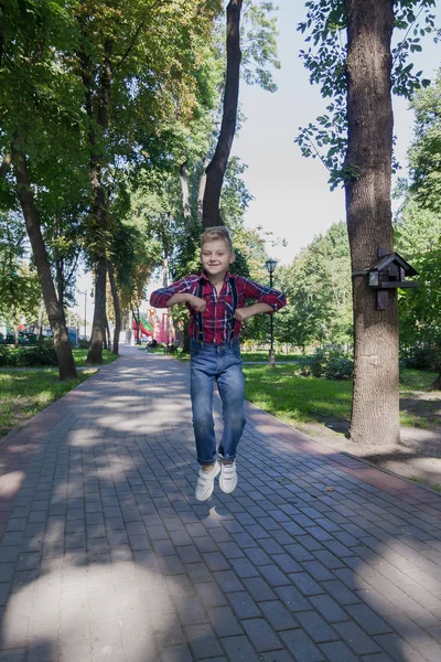 Gyönyörű fiú 7 éves jumping a parkban. — Stock Fotó