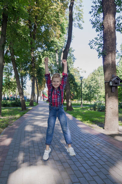 Beautiful boy 7 years old jumping in the park.