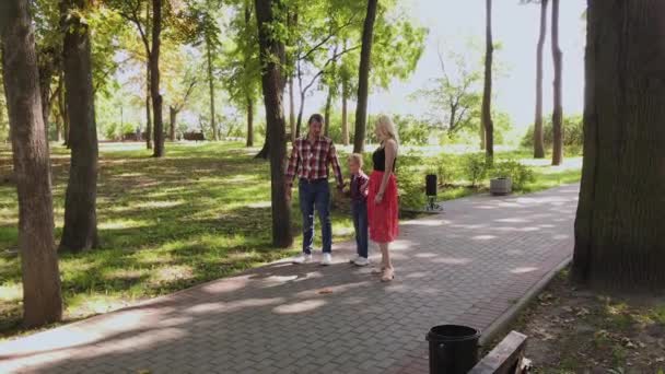 Feliz familia joven camina en el parque a lo largo del callejón . — Vídeos de Stock