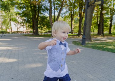 Küçük çocuk parktaki asfaltta koşuyor..