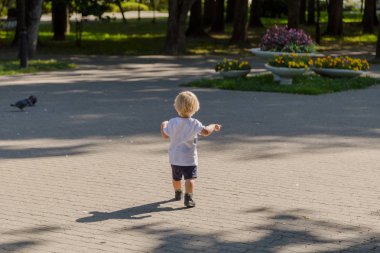 Küçük çocuk parktaki asfaltta koşuyor..