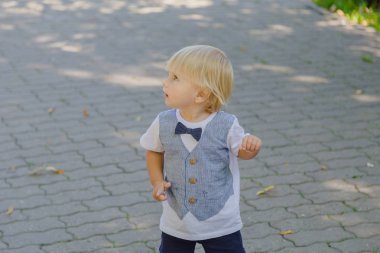 Küçük çocuk parktaki asfaltta koşuyor..