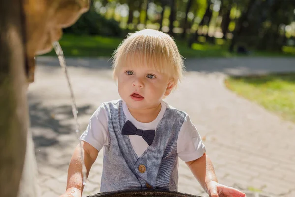 Gyönyörű kisfiú játszik egy patak víz a parkban. — Stock Fotó