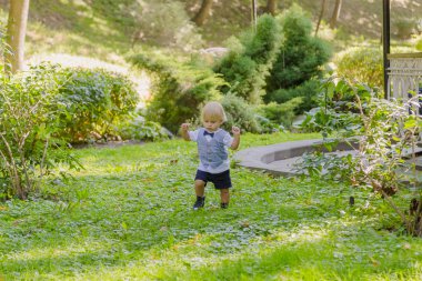 Parktaki yeşil çimenlikte mutlu küçük çocuk.