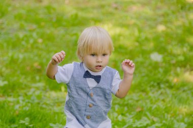 Parktaki yeşil çimenlikte mutlu küçük çocuk.