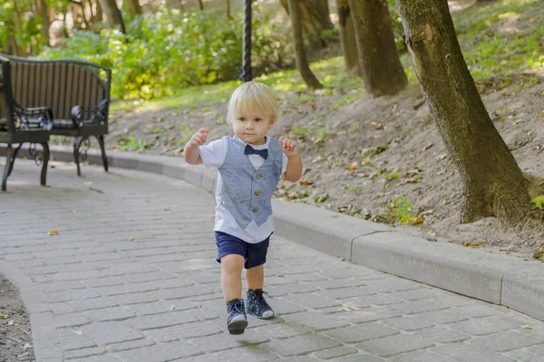 A kisfiú az aszfalton fut a parkban.. — Stock Fotó