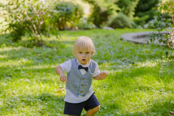 Menino feliz em um gramado verde em um parque . — Fotografia de Stock