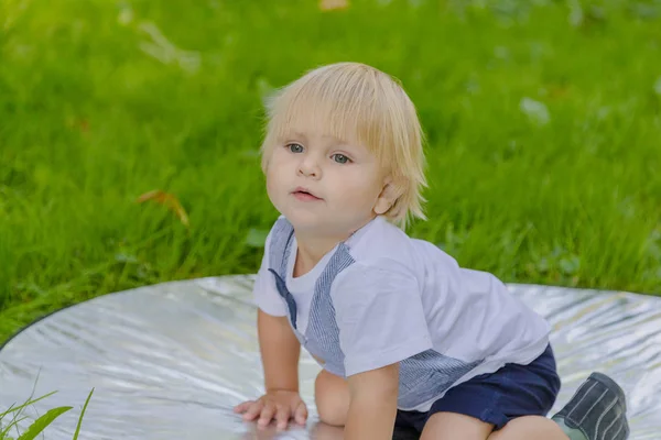Szczęśliwy chłopczyk na zielonym trawniku w parku. — Zdjęcie stockowe