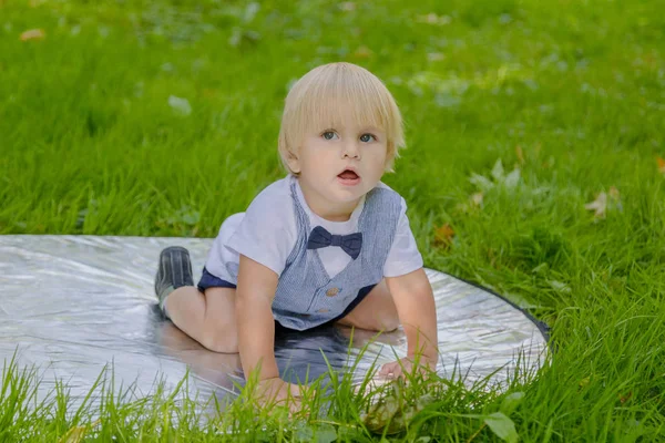 Szczęśliwy chłopczyk na zielonym trawniku w parku. — Zdjęcie stockowe