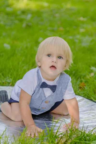 Joyeux petit garçon sur une pelouse verte dans un parc . — Photo