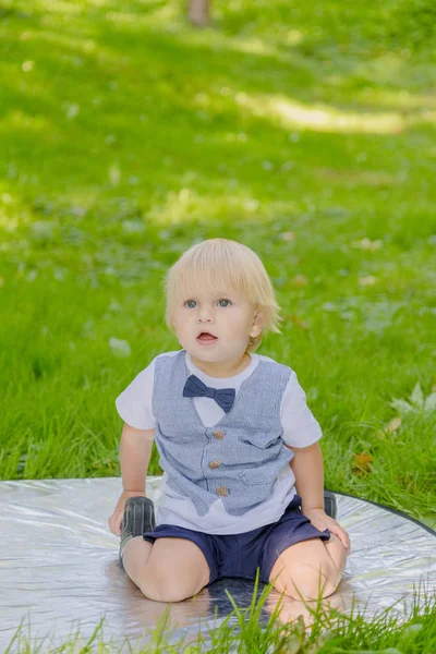 Šťastný malý chlapec na zeleném trávníku v parku. — Stock fotografie