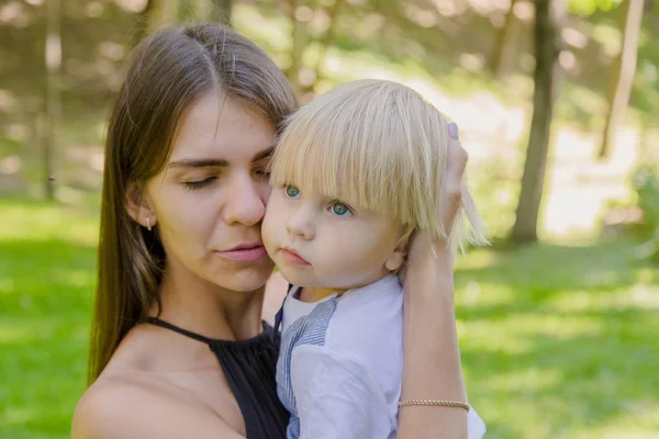 Çok üzgün anne ve küçük oğlu parkta kollarında..