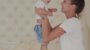 Güzel mutlu anne ve oğul beyaz yatakta oynuyorlar..