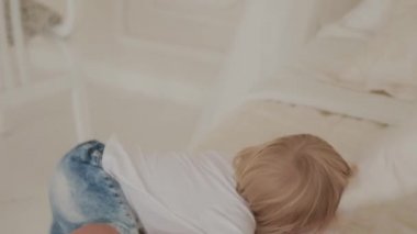 Güzel, mutlu küçük çocuk beyaz odada oynuyor..