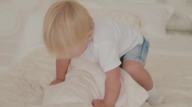 Güzel, mutlu küçük çocuk beyaz odada oynuyor..