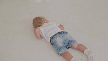 Güzel, mutlu küçük çocuk beyaz odada oynuyor..