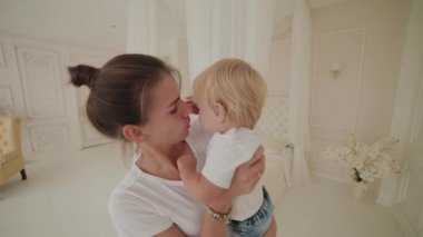 Güzel mutlu anne ve oğul beyaz yatakta oynuyorlar..