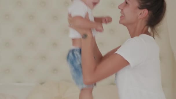 Bella mamma felice e figlio stanno giocando sul letto bianco . — Video Stock