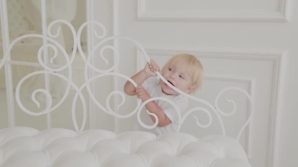 Schöner glücklicher kleiner Junge spielt im weißen Zimmer. — Stockvideo