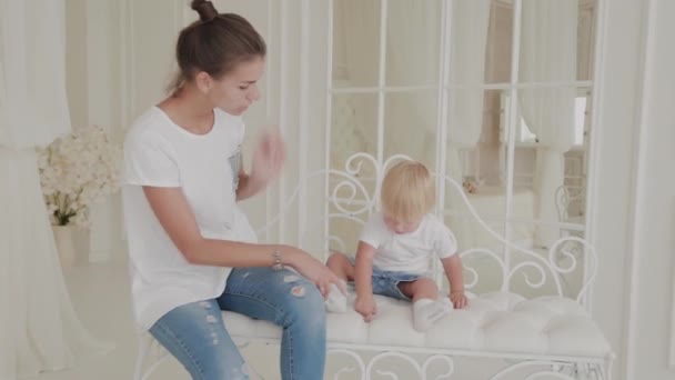 Schöne glückliche Mutter und Sohn spielen auf dem weißen Bett. — Stockvideo