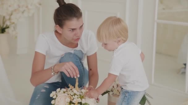 Hermosa madre feliz y el hijo están jugando en la cama blanca . — Vídeos de Stock