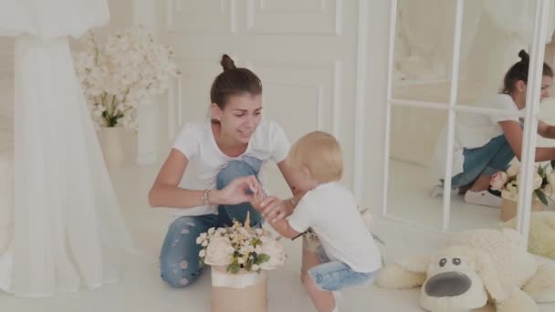 Hermosa madre feliz y el hijo están jugando en la cama blanca . — Vídeos de Stock