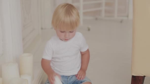 Mooi gelukkig jongetje speelt in de witte kamer. — Stockvideo