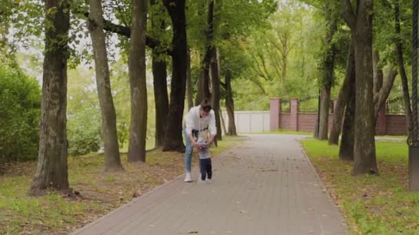 Lycklig mamma går med sin son i parken. — Stockvideo