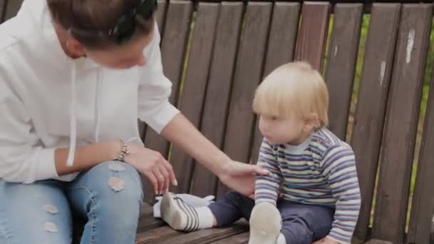 Madre feliz con su hijo en un banco en el parque . — Vídeos de Stock