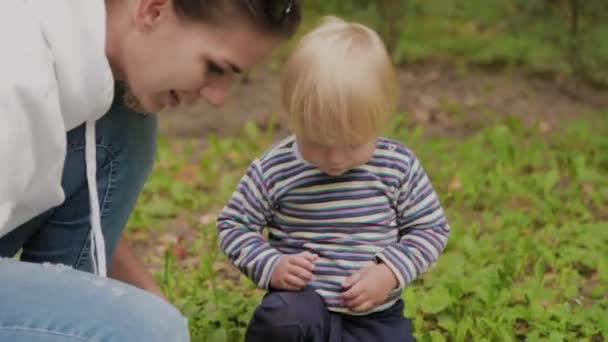 Gelukkig moeder met haar zoon speelt op het gras. — Stockvideo