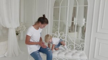 Güzel mutlu anne ve oğul beyaz yatakta oynuyorlar..