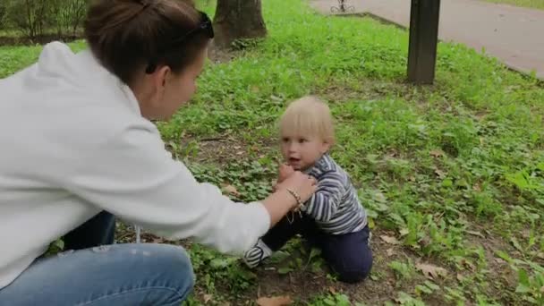Glückliche Mutter mit ihrem Sohn spielt auf dem Rasen. — Stockvideo
