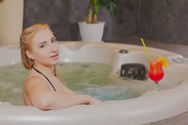 Hermosa chica con un cóctel en un jacuzzi . — Foto de Stock