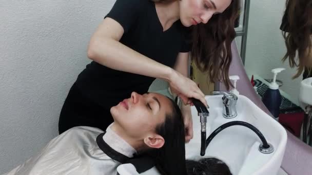 Mooi jong meisje wassen hun haar op de kapper. — Stockvideo