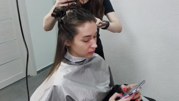 Cabeleireiro menina seca o cabelo ao cliente com secador de cabelo no cabeleireiro . — Vídeo de Stock